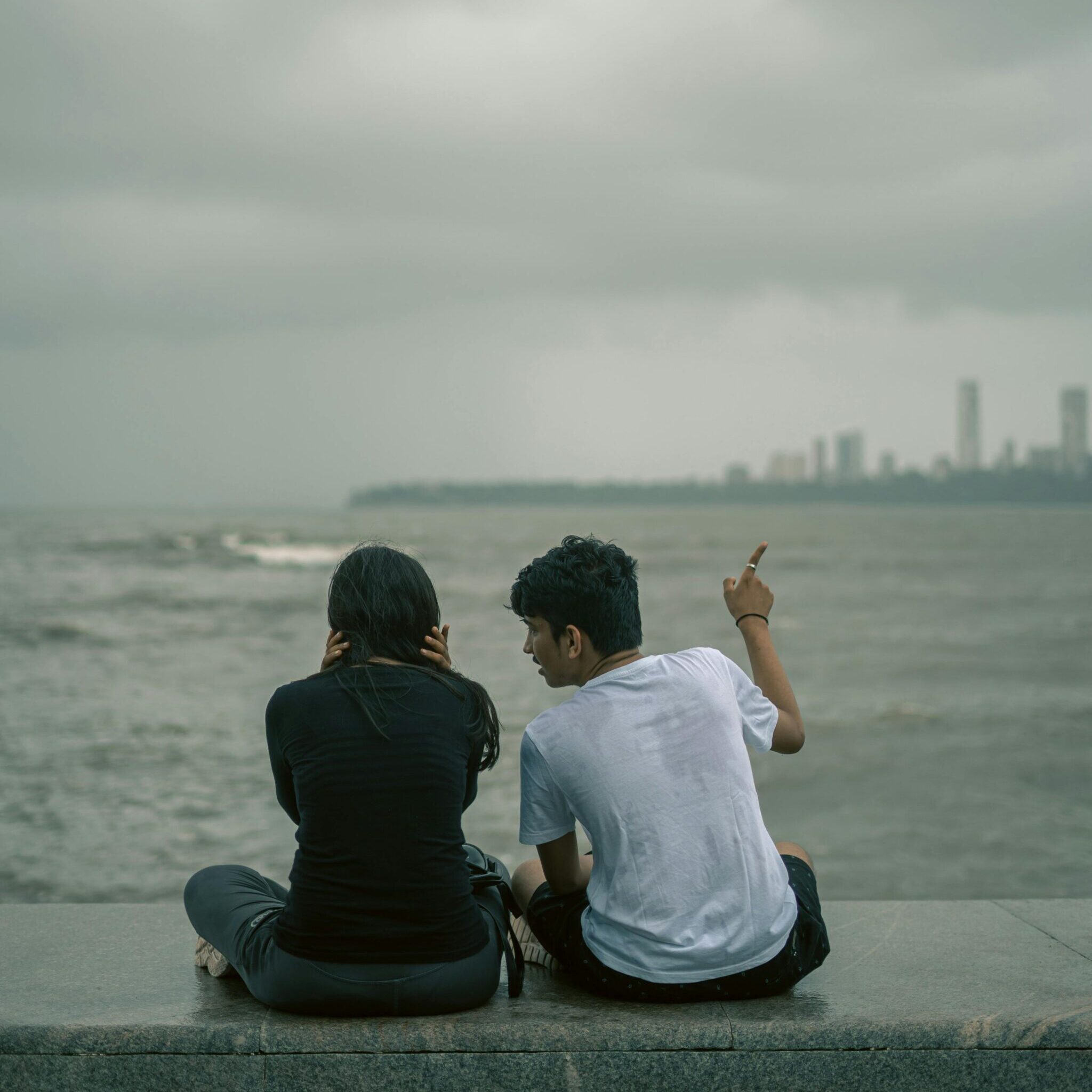 Couple Sitting by the Sea on an Overcast Day